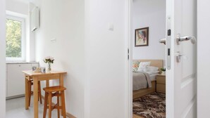 Een modern interieur met een houten eettafel en stoelen, een bed met bloemenbeddengoed en een schilderij aan de muur.