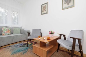 A living room with a sofa, two chairs, a coffee table, and a rug. - Family Apartment for 8 People | Close to the Park (Warszawa)