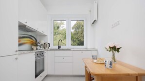 Een moderne keuken met witte kasten, een ingebouwde oven, een dubbele spoelbak en een raam met uitzicht op bomen.
