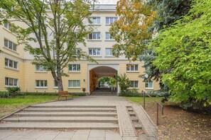 A multi-story building with a central archway, surrounded by greenery and a paved walkway leading to the entrance. - Family Apartment for 8 People | Close to the Park (Warszawa)