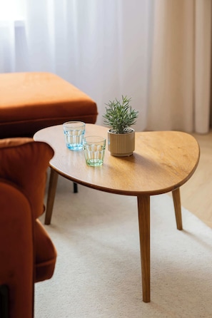 A round wooden coffee table with two glass vases and a potted plant. - Elegant Apartment in Center | By the Market (Warszawa)