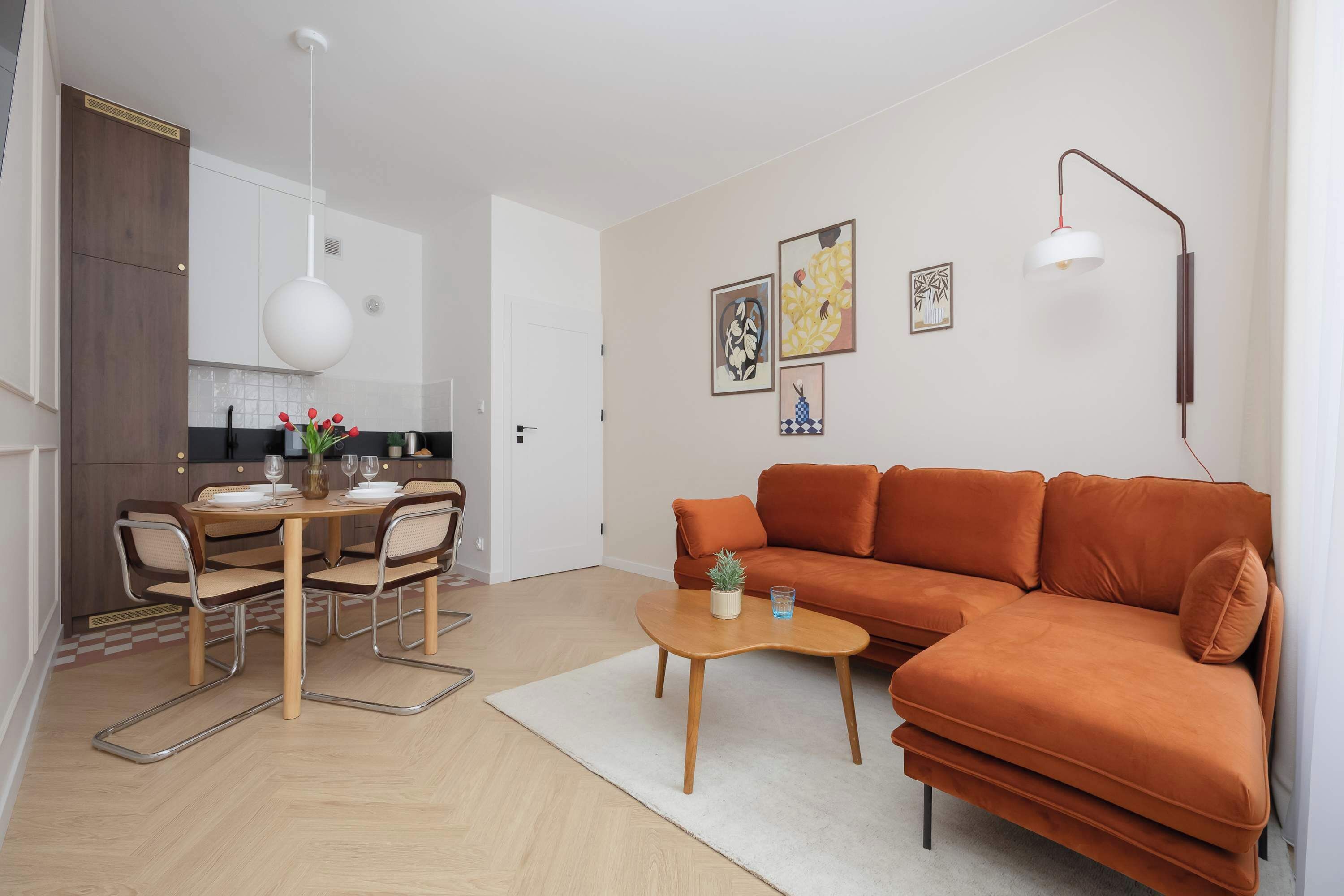 A modern living room with a sofa, coffee table, and dining area with chairs and a table.