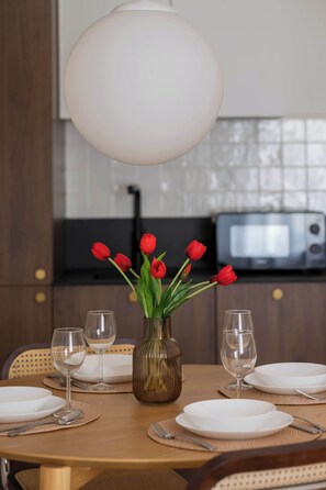 A dining table set with plates, cutlery, and a vase with red tulips. - Elegant Apartment in Center | By the Market (Warszawa)