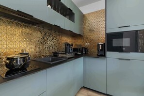 Eine moderne Küche mit schwarzem Arbeitsplatz, Edelstahlgeräten und einer gemusterten Spritzschutzwand.