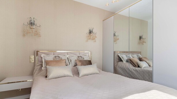Une chambre moderne avec un grand lit, une table de chevet et un miroir.