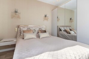 A modern bedroom with a large bed, a bedside table, and a mirror. - Exclusive Apartment with Garden | Air Conditioning (Jastrzębia Góra)