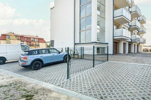 Ein modernes Gebäude mit Parkplatz, einem blauen Auto und einem weißen Lieferwagen.