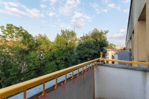 A balcony with a yellow railing overlooking a cityscape with trees and buildings. - Mosaic Apartment with Air Conditioning | Center (Rzeszów)