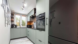 Eine Küche mit Einbauofen, Kühlschrank und einem Fenster mit Jalousien.