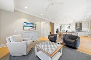 A spacious living area with a sofa, armchairs, a coffee table, and a painting of a beach scene. - New Oceanfront Jekyll Home • Beach Boardwalk • Fireplace Porch (Jekyll Island)