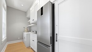 A modern kitchen with white cabinetry, a stainless steel refrigerator, and a built-in oven. - New Oceanfront Jekyll Home • Beach Boardwalk • Fireplace Porch (Jekyll Island)