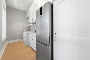 A modern kitchen with white cabinetry, a stainless steel refrigerator, and a built-in oven.
