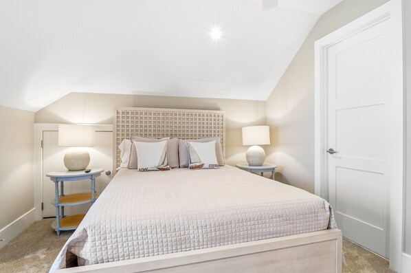 A bedroom with a bed, two bedside tables, a headboard, and a door.