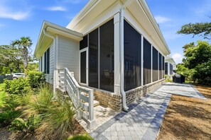Ein Haus mit einer überdachten Veranda, einem steinernen Fundament und einem Ziegelweg, der zum Eingang führt.