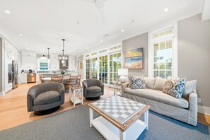 A spacious living area with a sofa, armchairs, a coffee table, and a dining table with chairs. - New Oceanfront Jekyll Home • Beach Boardwalk • Fireplace Porch (Jekyll Island)