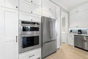 A modern kitchen with stainless steel appliances, white cabinetry, and a patterned backsplash. - New Oceanfront Jekyll Home • Beach Boardwalk • Fireplace Porch (Jekyll Island)