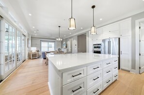 A spacious kitchen with a large island, white cabinetry, stainless steel appliances, and pendant lighting. - New Oceanfront Jekyll Home • Beach Boardwalk • Fireplace Porch (Jekyll Island)