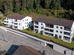 Un moderno edificio de apartamentos con varios balcones, un estacionamiento y una calle al frente.