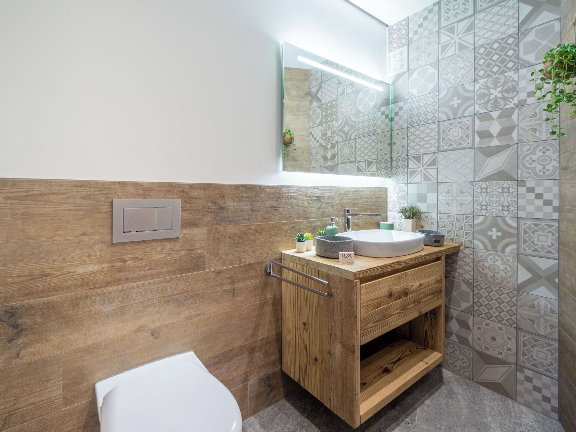 A modern bathroom with a wooden vanity, a white sink, and a mirror above it.