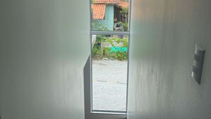 A staircase leading to a balcony with a view of a red-roofed building and a green area. - Lumina Riviera Ferrugem (Garopaba)