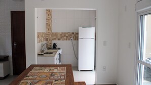 A kitchen with a refrigerator, a sink, and a tiled backsplash. - Lumina Riviera Ferrugem (Garopaba)