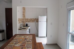 A kitchen with a refrigerator, a sink, and a tiled backsplash. - Lumina Riviera Ferrugem (Garopaba)