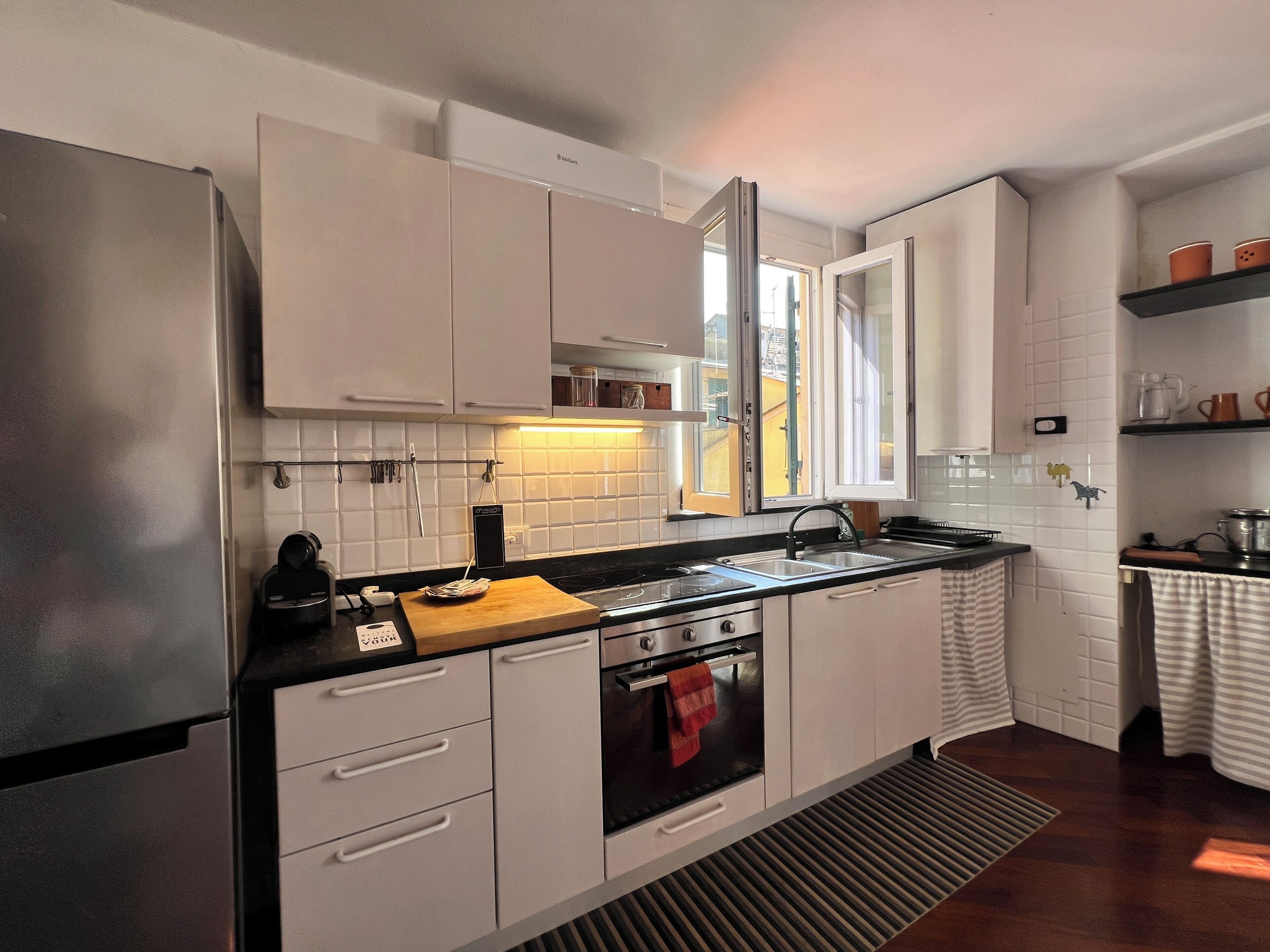 Eine moderne Küche mit weißen Schränken, einem Edelstahlkühlschrank, einer Holz Arbeitsplatte und einem eingebauten Backofen.