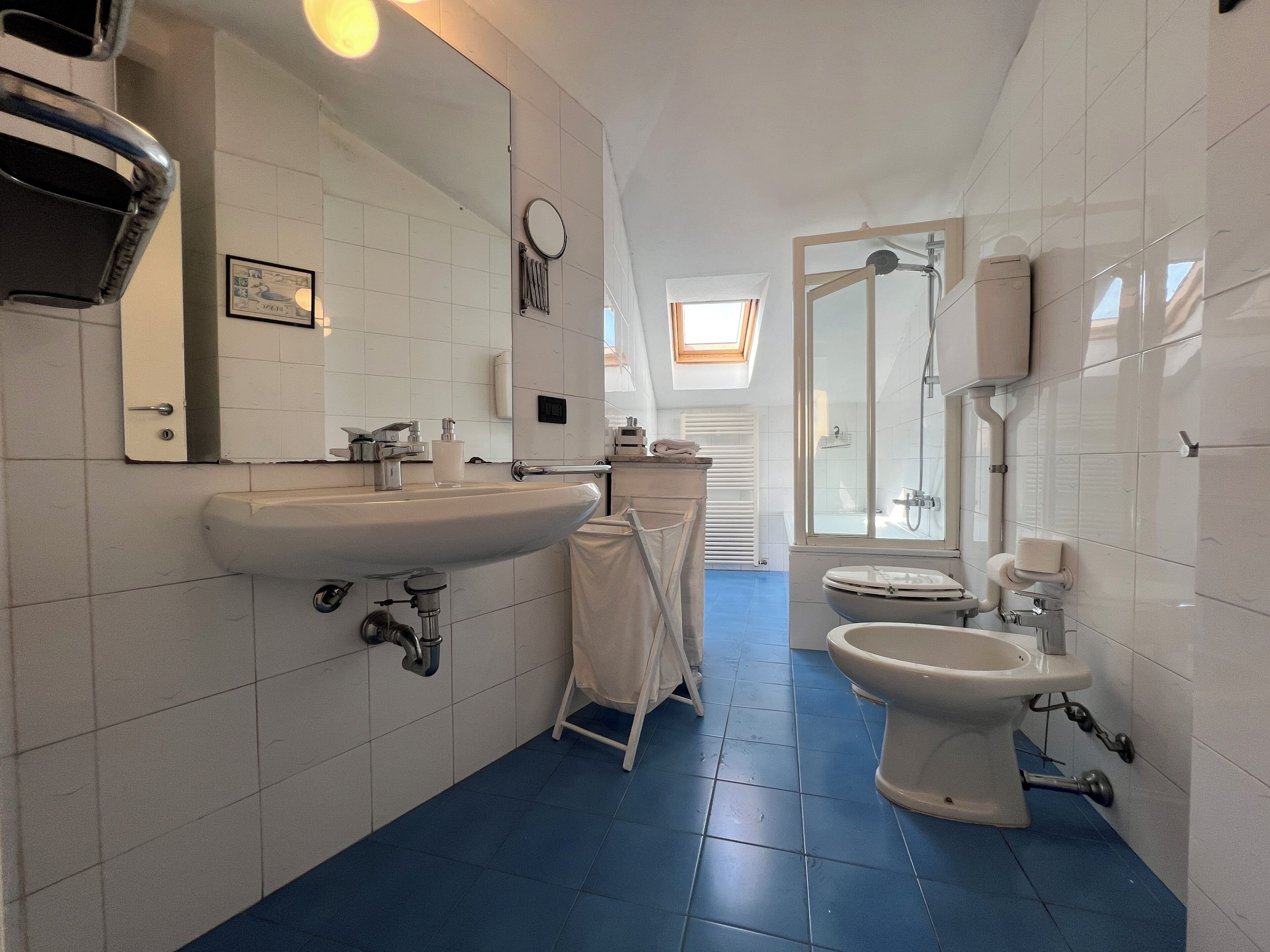 A bathroom with a large sink, toilet, and shower area.