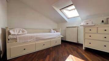 Un dormitorio con literas, cómoda, radiador y tragaluz.