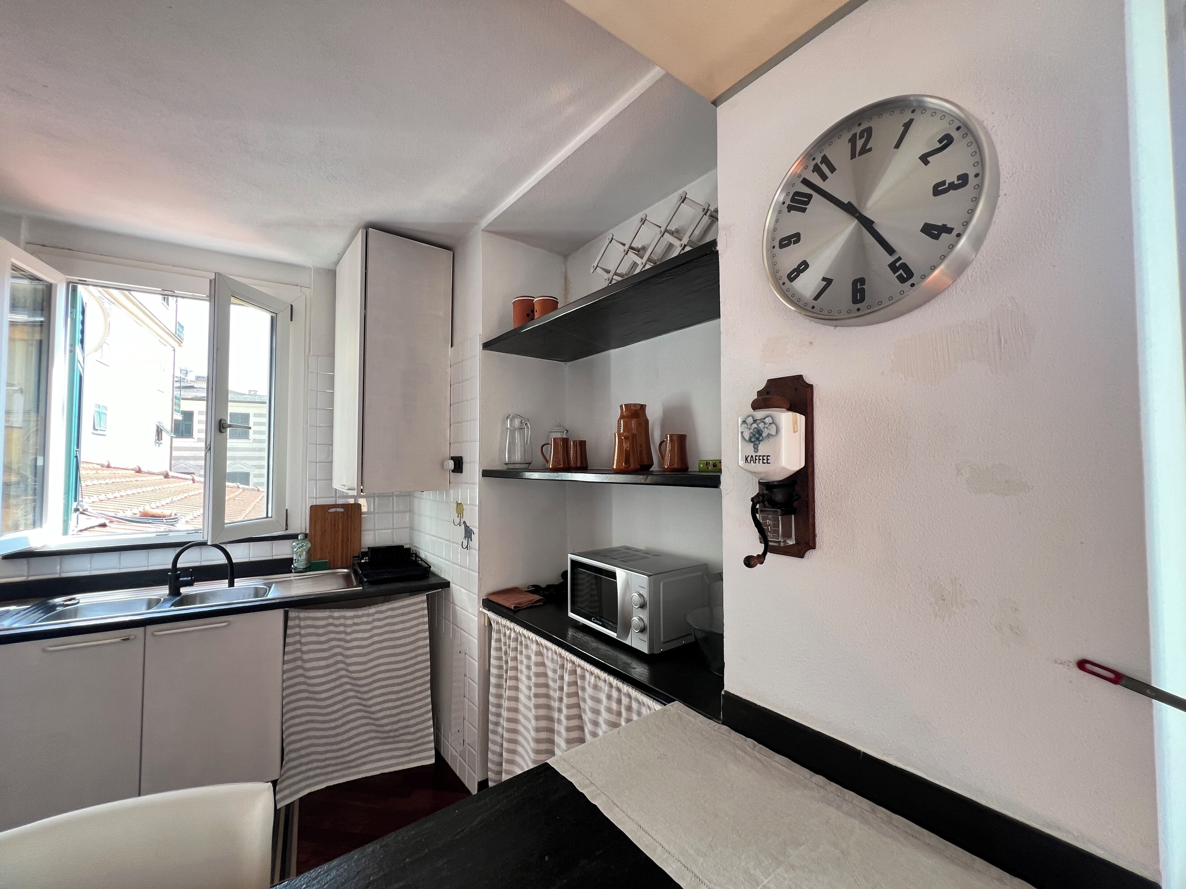 A compact kitchen with a window, a microwave, a kettle, and a coffee machine.