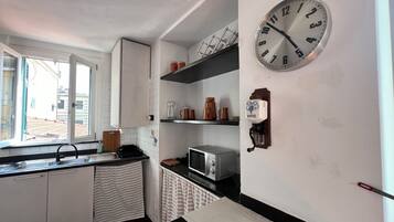 A compact kitchen with a window, a microwave, a kettle, and a coffee machine.