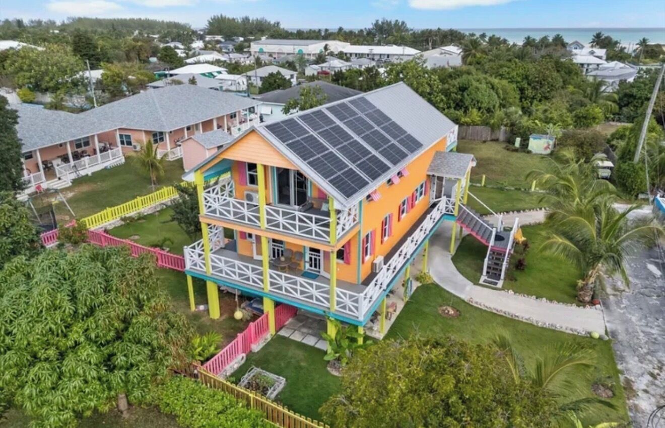 A multi-story building with a balcony, solar panels, and a fenced yard.