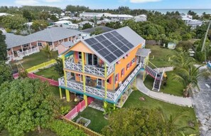 Un edificio de varios pisos con balcón, paneles solares y un patio cercado.