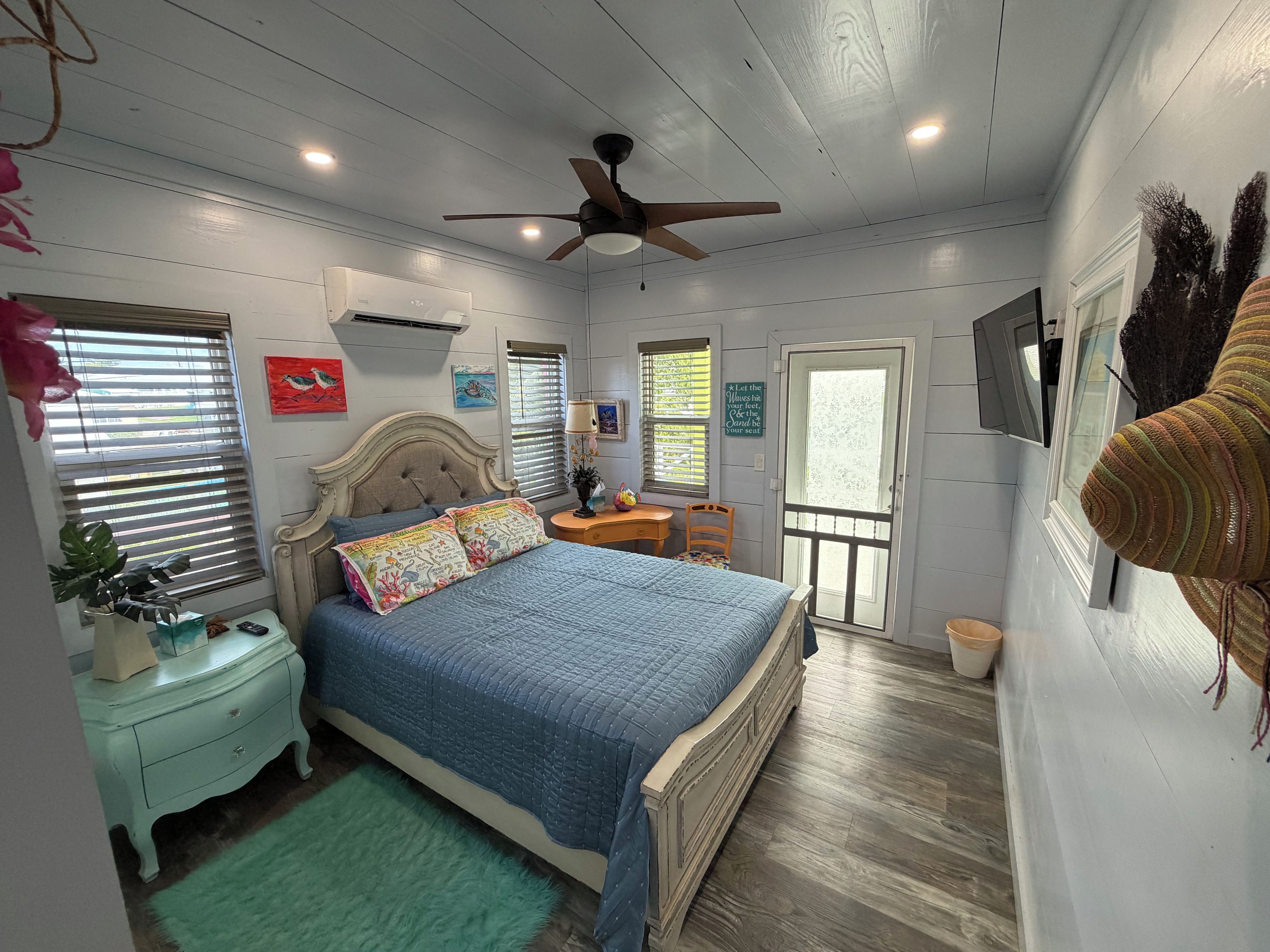 Une chambre à coucher avec un lit, un ventilateur de plafond, un bureau et une chaise.