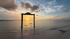 A swing set on a beach with a sunset in the background. - Codakai the ultimate Spanish Wells family friendly getaway (Spanish Wells)