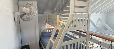 A loft-style bedroom with a bunk bed, a fan, and a view of the outdoors.
