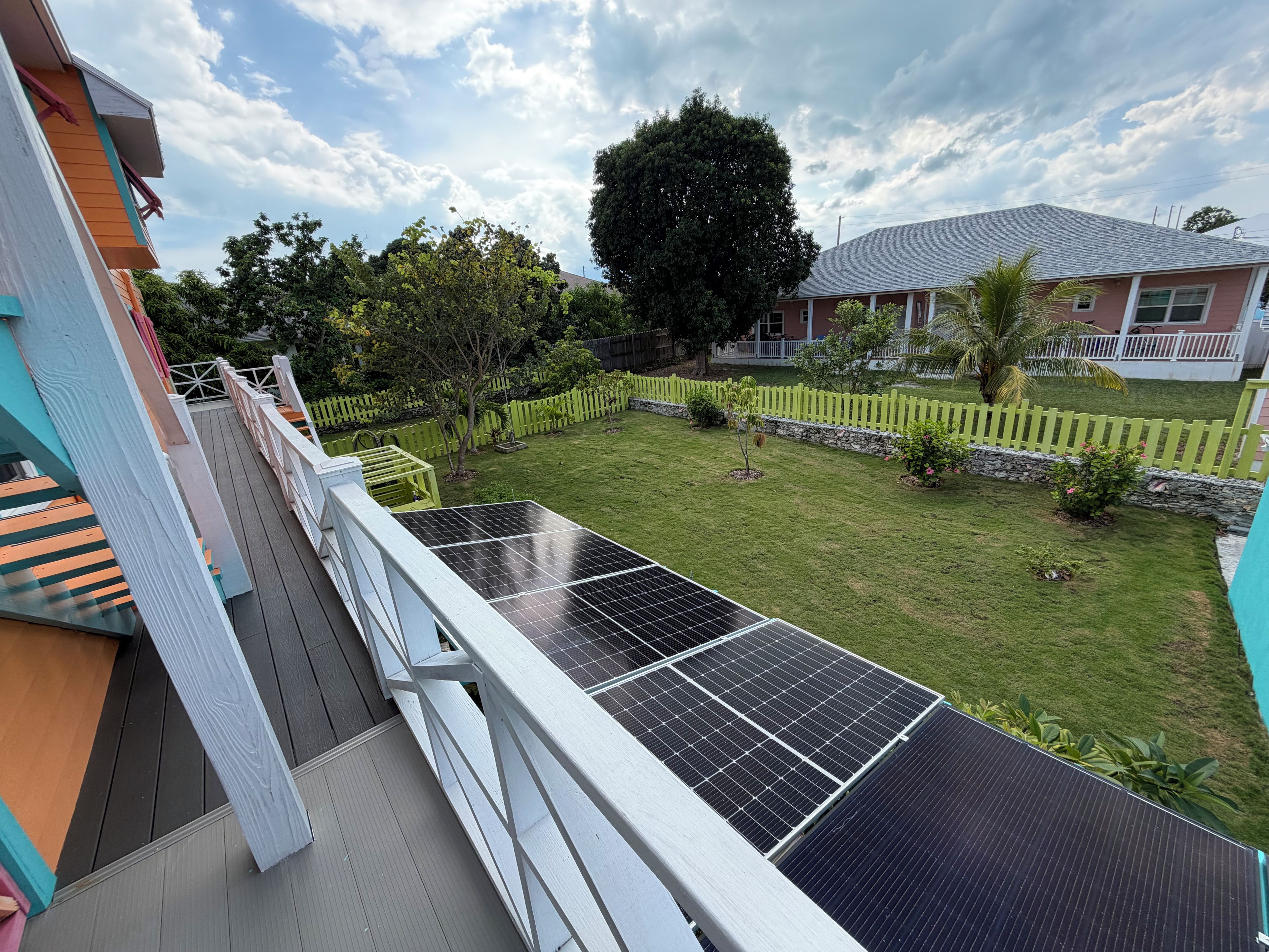 Ein Wohnhaus mit einer Solaranlage, einem eingezäunten Garten und Blick auf die Nachbarhäuser.