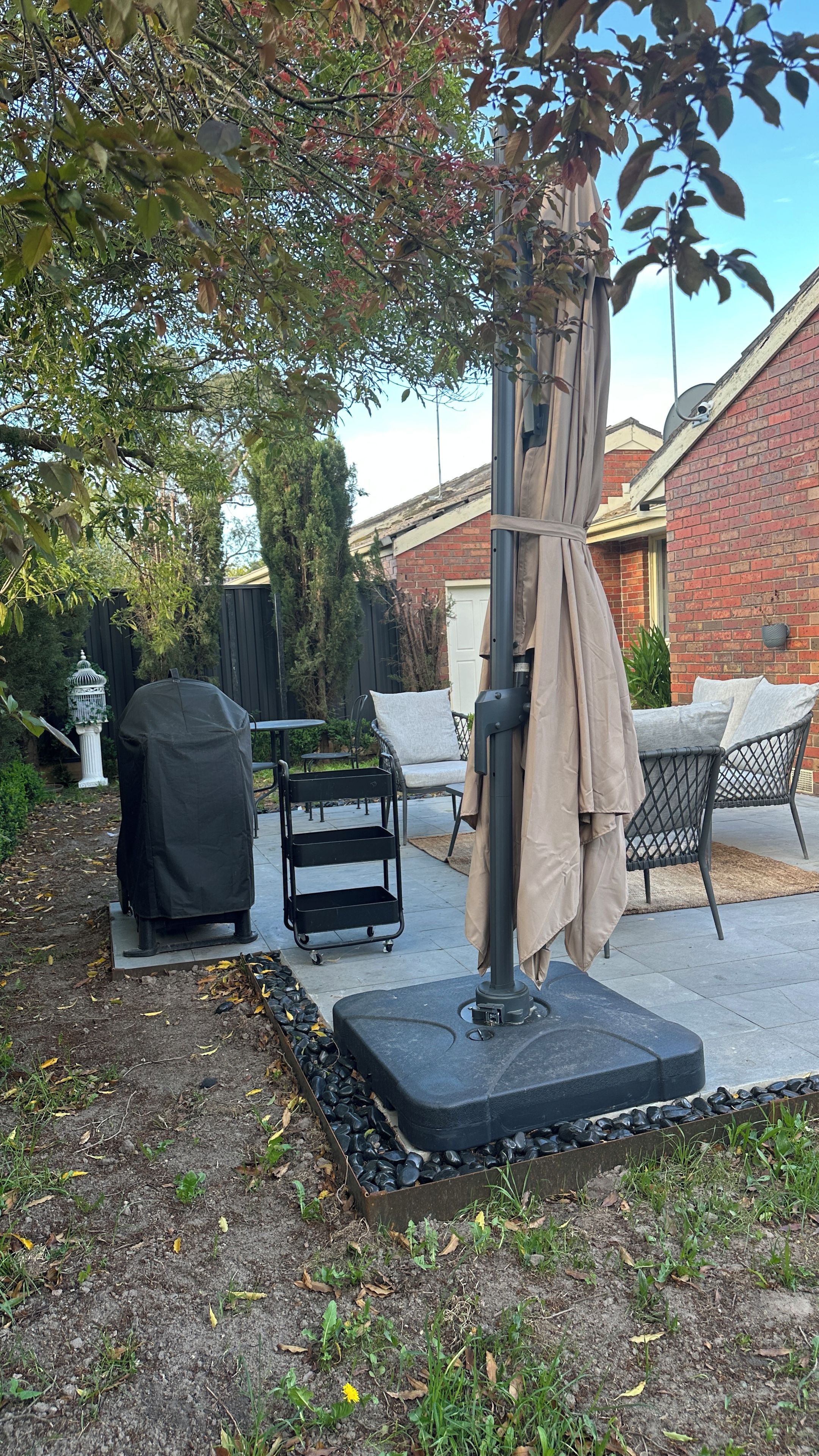 Un espace patio extérieur doté d’un barbecue couvert, de mobilier d’extérieur et d’un lampadaire décoratif.