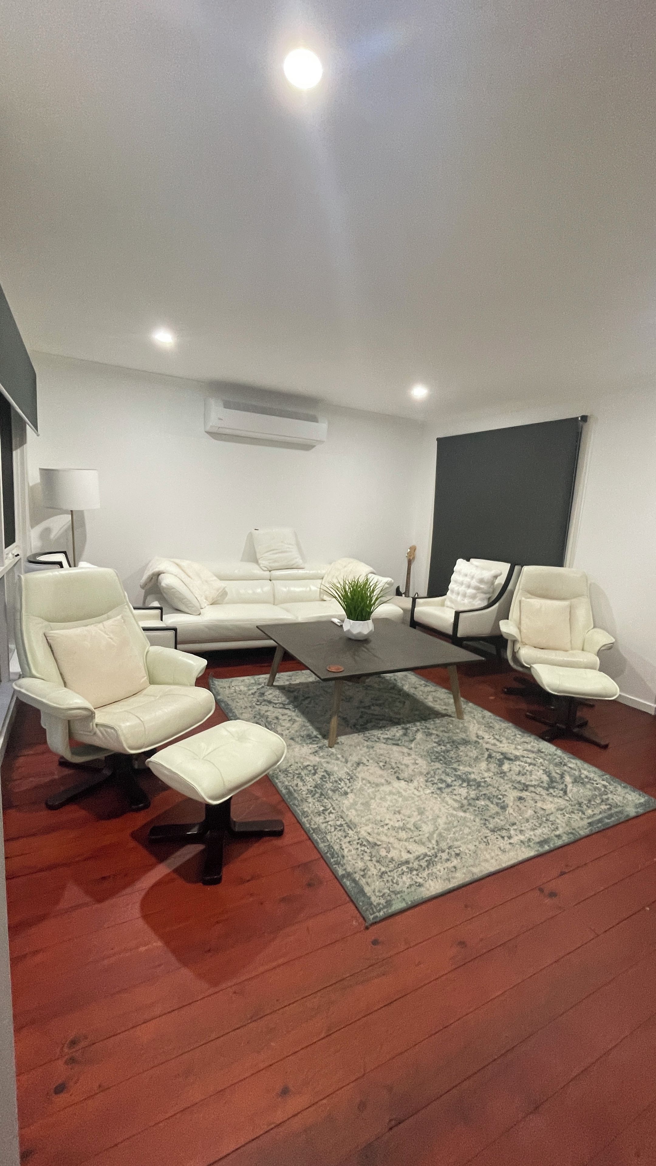 A modern living room with a white sofa set, a coffee table, and a patterned rug.