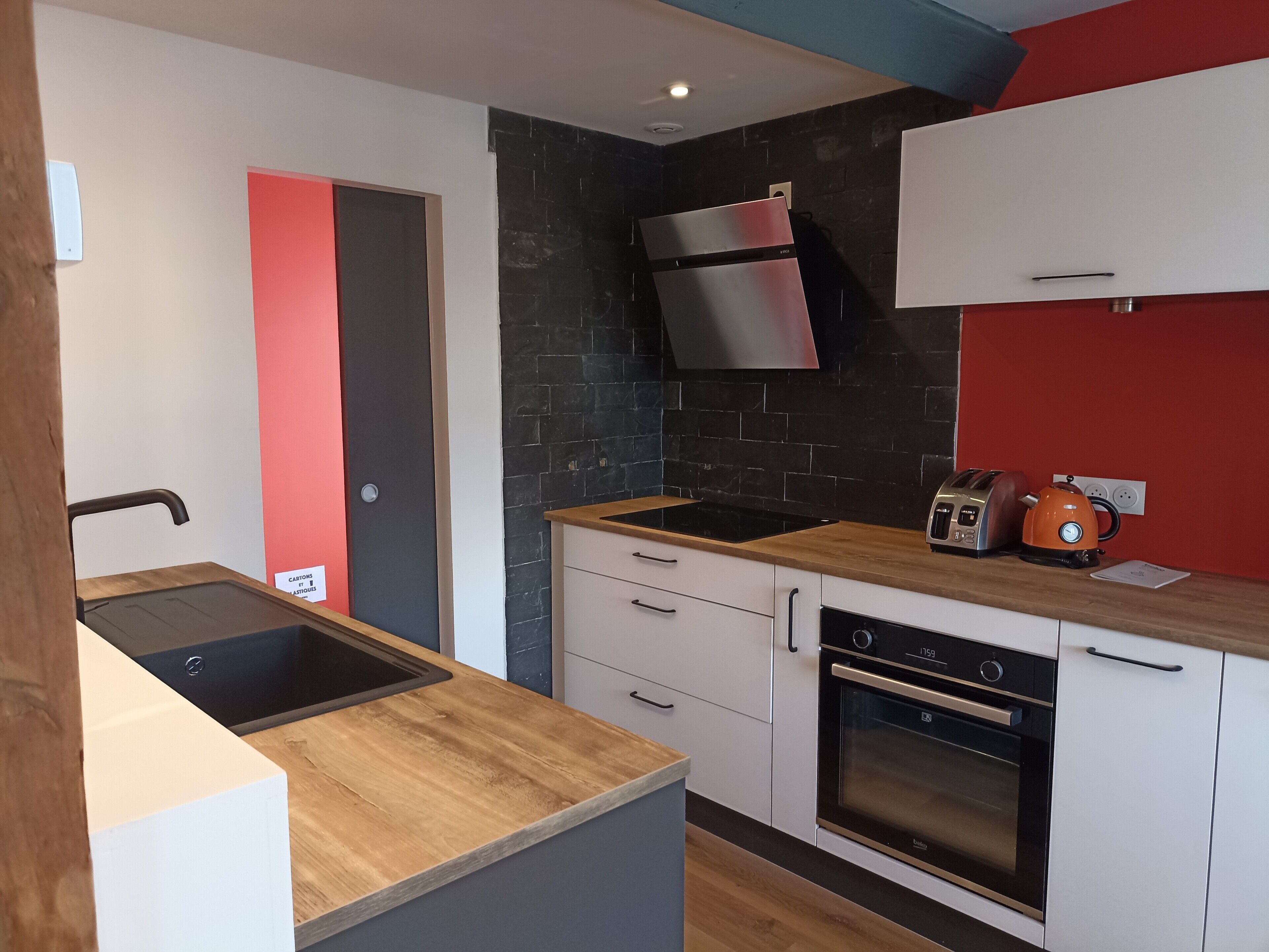 A modern kitchen with a built-in oven, a stainless steel range hood, and a toaster.
