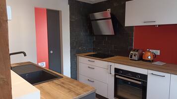 A modern kitchen with a built-in oven, a stainless steel range hood, and a toaster.