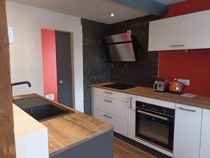 A modern kitchen with a built-in oven, a stainless steel range hood, and a toaster.