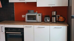 A kitchen with white cabinets, a microwave, toaster, kettle, and a dishwasher. - Beautiful Apartment in the Heart of Les Rousses Village (Les Rousses)