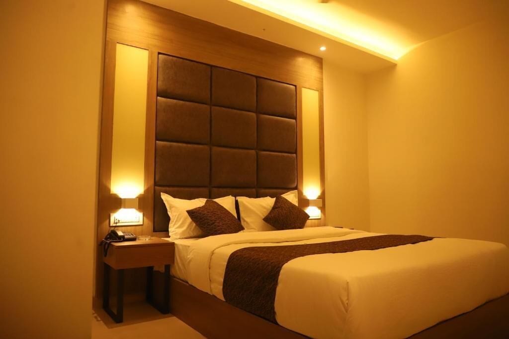 Ein Hotelzimmer mit einem großen Bett, einem gepolsterten Kopfteil, Nachttischlampen und einem Nachttisch mit Telefon.