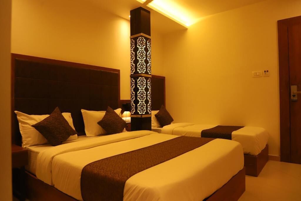 Habitación de hotel con dos camas, un pilar decorativo y una puerta de madera.