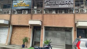 Ein Hotel mit einer Fassade, auf der die Schilder 'Hotel SAI Pritam' und 'Hotel Abrol Suites' zu sehen sind.