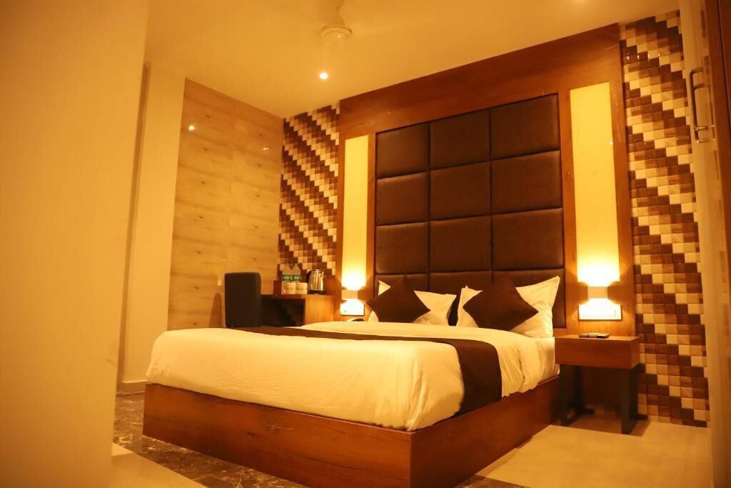A modern hotel room with a large bed, a wooden headboard, and a wall with a geometric pattern.