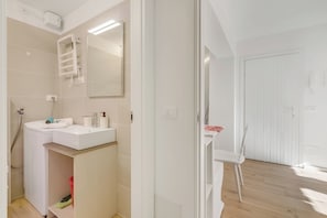 Uma casa de banho moderna com uma pia branca, espelho e porta-toalhas.