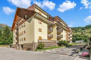 Un hotel de varios pisos con balcones y un estacionamiento.