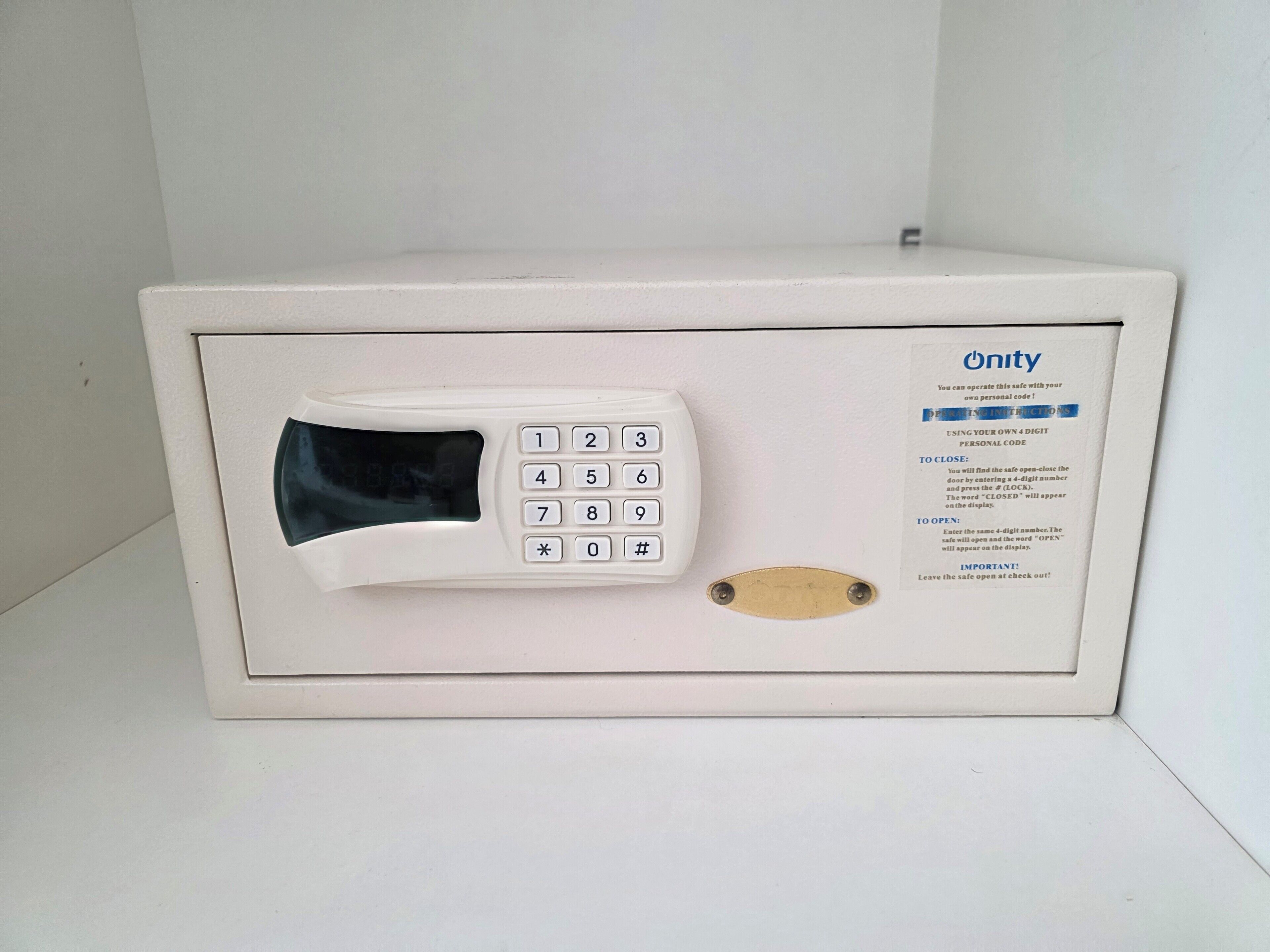 A white safe with a keypad and a card slot, labeled 'Unity' with instructions for operation.